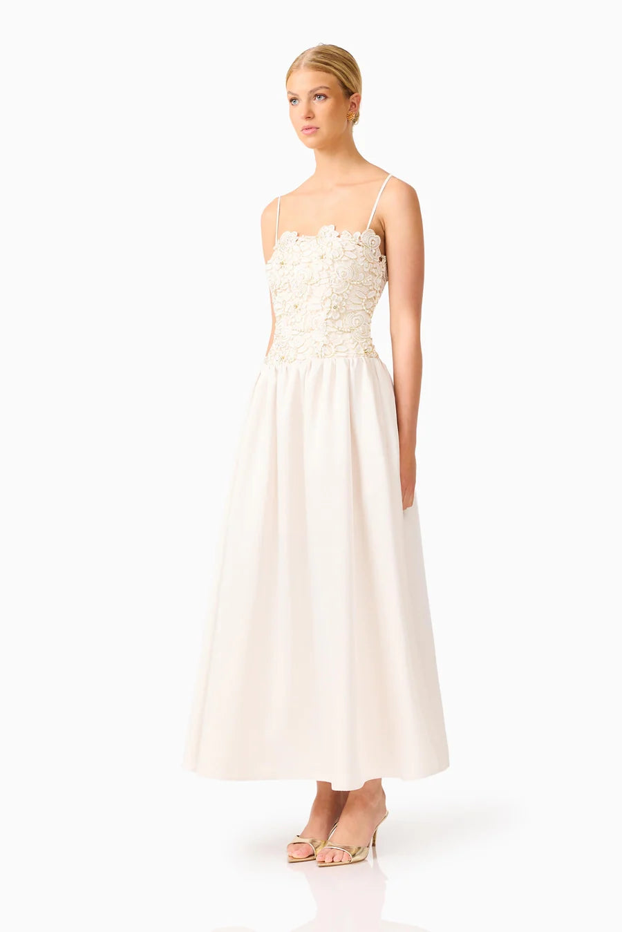 A model showcases a stunning ivory gown featuring delicate floral detailing on the bodice and a flowy skirt, perfect for bridal events, proms, or formal occasions. This elegant dress is conveniently located near Apex, Cary, and Raleigh.