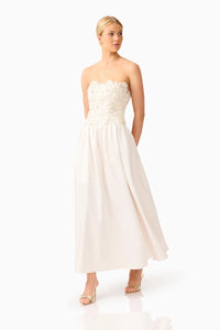 A model showcases a stunning ivory gown featuring intricate floral lace detailing on the strapless bodice and a flowing skirt, perfect for bridal events, galas, or formal occasions.