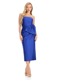 A model showcases the ASHLEYlauren E4921, a striking strapless royal blue midi dress featuring a unique side bow detail.
