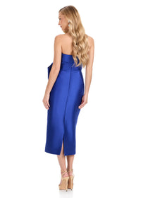 A model is wearing a stunning royal blue strapless midi dress, showcasing a sleek design with a slight back slit.
