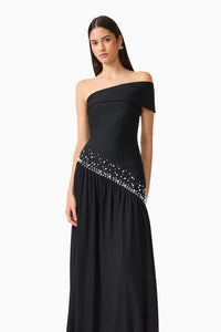 A model showcases the elegant Natasia Off-Shoulder Gown in Black, featuring a flattering silhouette and delicate embellishments along the skirt.