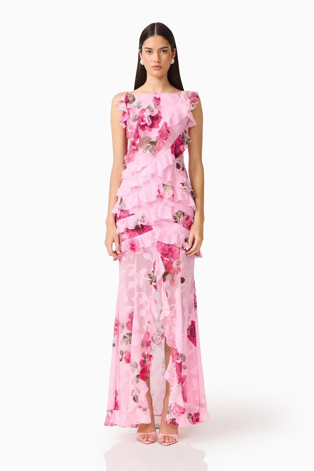 A model showcases a stunning sleeveless pink floral gown featuring cascading ruffles and a sheer overlay, perfect for elegant occasions like weddings or galas. This romantic dress is conveniently located near Apex, Cary, and Raleigh.