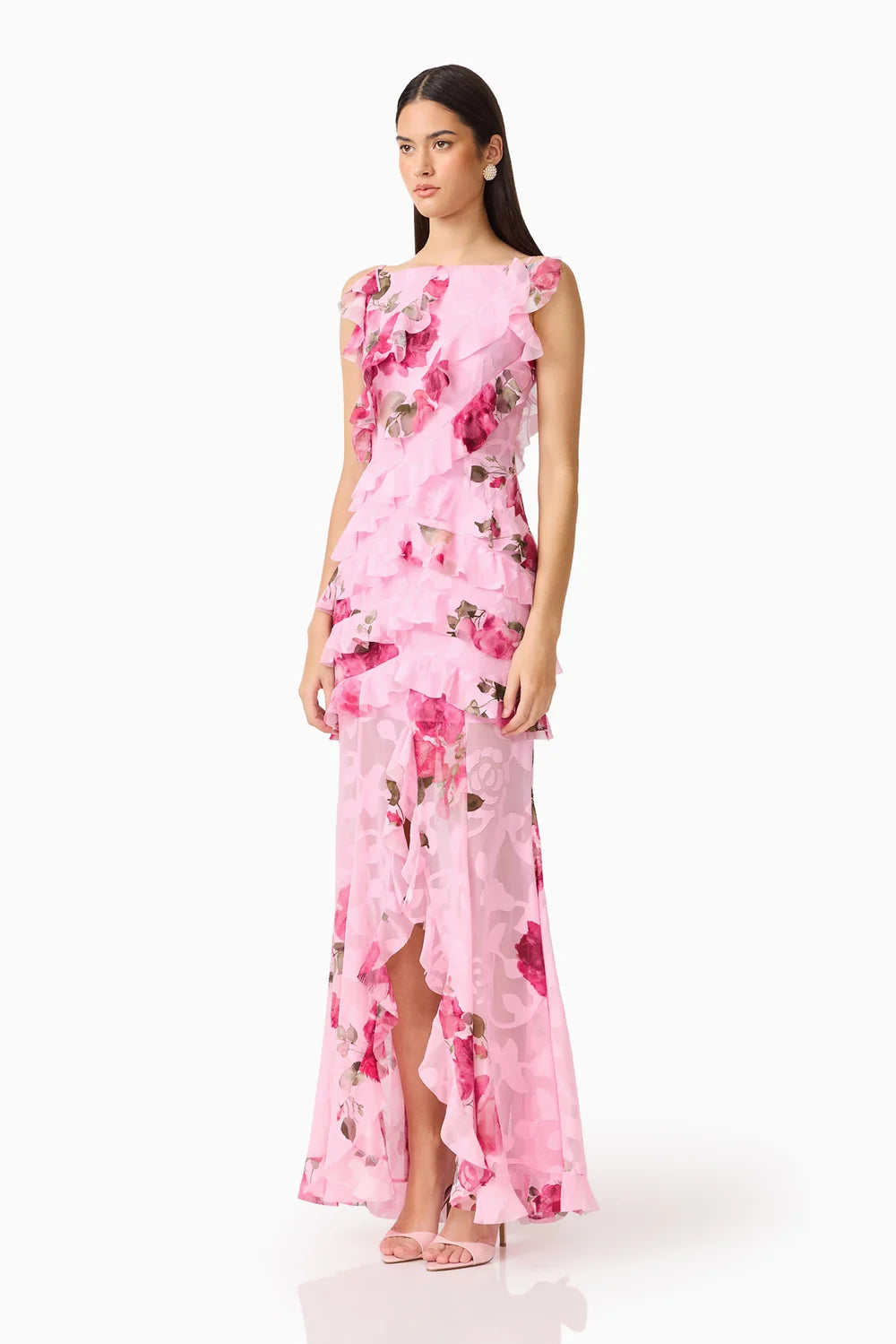 A model showcases a stunning pink floral gown featuring ruffles and a thigh-high slit, perfect for elegant occasions like weddings, proms, or galas. This exquisite dress is conveniently available near Apex, Cary, and Raleigh.