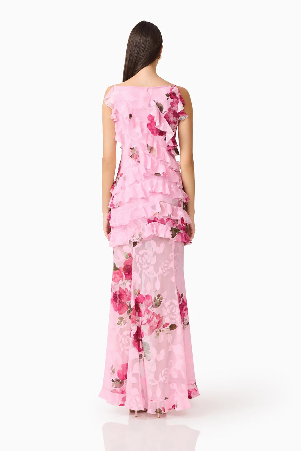 A woman is seen from the back wearing a sleeveless pink floral gown featuring ruffled layers, ideal for elegant occasions such as weddings, proms, or galas. This stunning dress is conveniently available near Apex, Cary, and Raleigh.