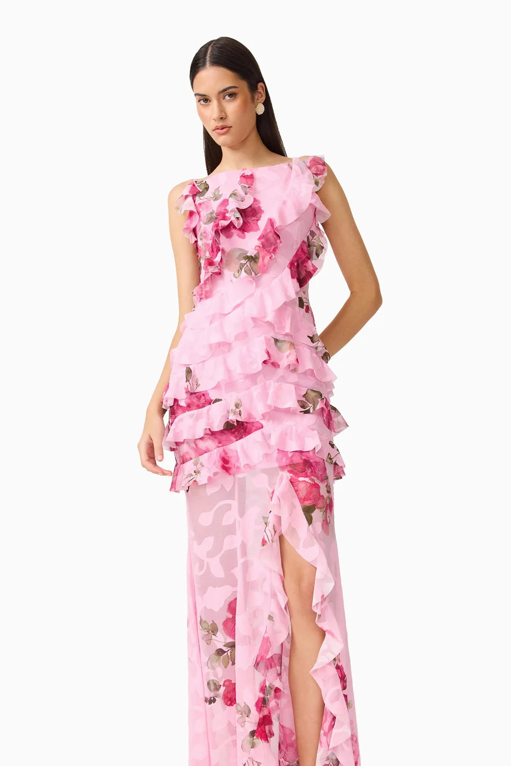 A model wears a stunning pink floral gown featuring layers of ruffles and a thigh-high slit, perfect for elegant occasions such as weddings, proms, or galas. This dress is conveniently located near Apex, Cary, and Raleigh.