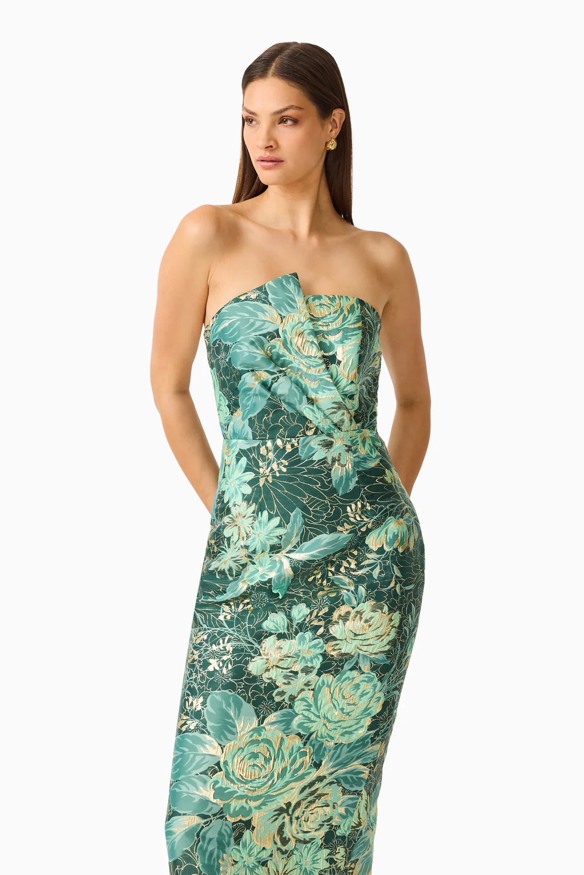A model showcases a strapless, floral midi dress featuring shades of teal and green, elegantly draped for a flattering silhouette.