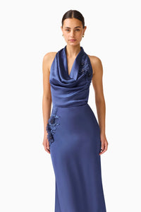 A model showcases a sophisticated navy cowl neck gown featuring elegant floral embroidery on one side. This stunning dress is perfect for memorable occasions like galas or black tie weddings, and is available near Apex, Cary, and Raleigh.