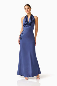 A model poses in an elegant navy cowl neck gown featuring intricate floral embroidery on one side. This sophisticated dress is perfect for memorable occasions like proms, galas, or black tie weddings, and is available near Apex, Cary,.