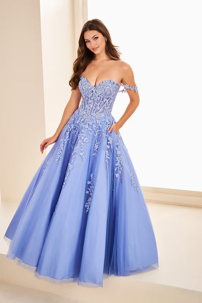 A model poses in a stunning off-the-shoulder blue gown with intricate lace detailing and a corset bodice.
