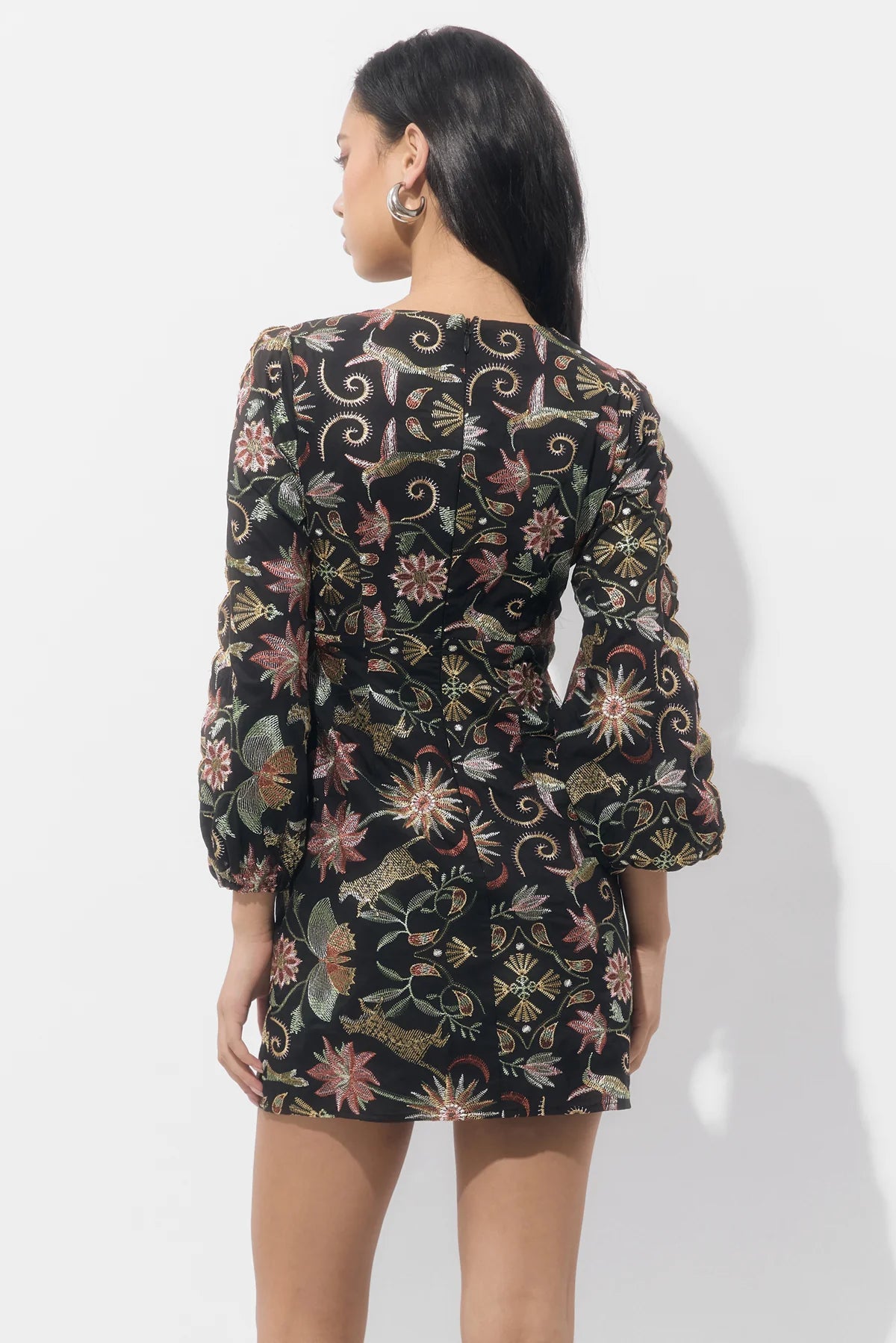 A model showcases a stylish mini dress featuring intricate floral embroidery and puffed sleeves, ideal for casual outings like birthday parties or date nights. This trendy piece is conveniently available near Apex, Cary, and Raleigh.