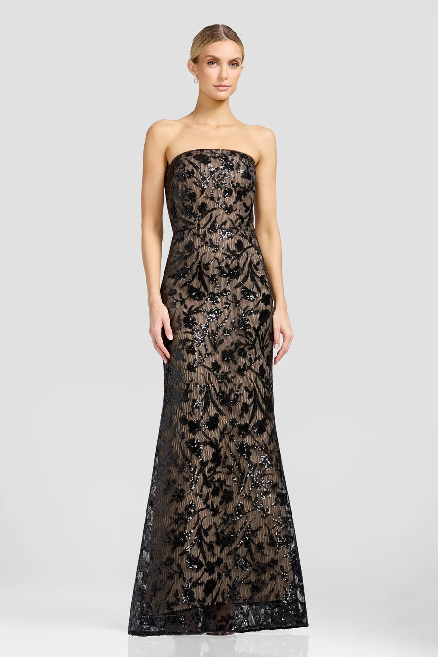 A model showcases a stunning strapless black evening gown adorned with intricate floral patterns and shimmering embellishments.