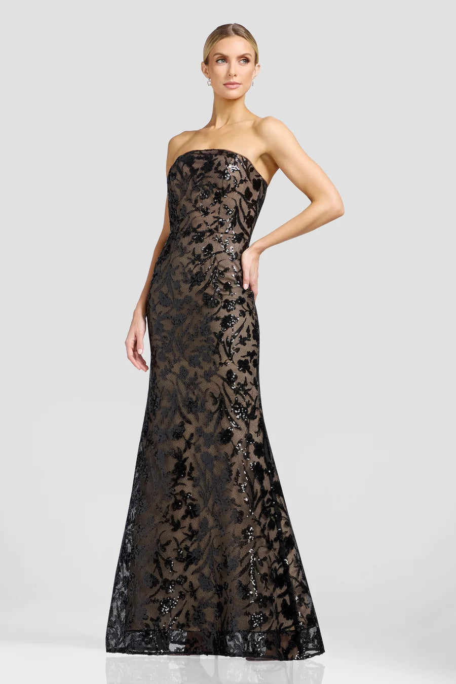 A model showcases a stunning strapless evening gown in a sophisticated black and gold floral design, perfect for a black tie wedding or gala.