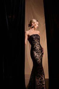A model gracefully poses in a stunning strapless gown featuring intricate black lace patterns against a nude underlay, accentuating her silhouette.