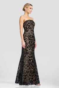 A model showcases a stunning strapless evening gown featuring intricate black floral patterns and shimmering embellishments.