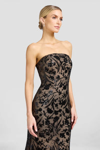 A model showcases a stunning strapless black gown adorned with intricate floral patterns and sequins, perfect for an elegant evening event such as a gala or black-tie wedding.