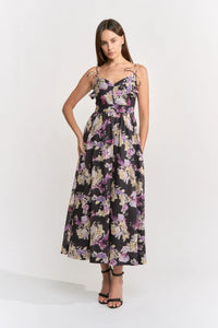 A model showcases a floral midi dress with a sweetheart neckline and adjustable shoulder ties, perfect for casual outings like birthday parties or date nights. This stylish dress is conveniently located near Apex, Cary, and Raleigh.
