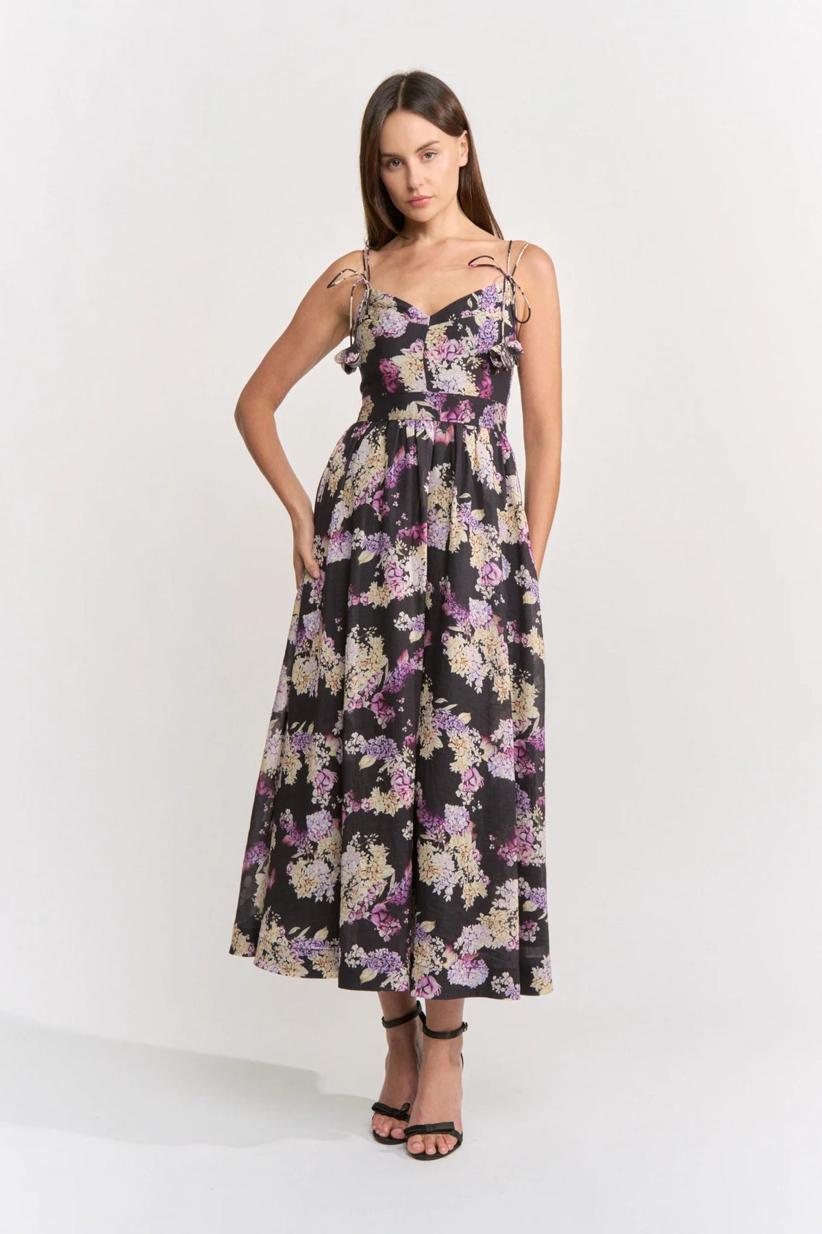 A model showcases a floral midi dress with a sweetheart neckline and adjustable shoulder ties, perfect for casual outings like birthday parties or date nights. This stylish dress is conveniently located near Apex, Cary, and Raleigh.