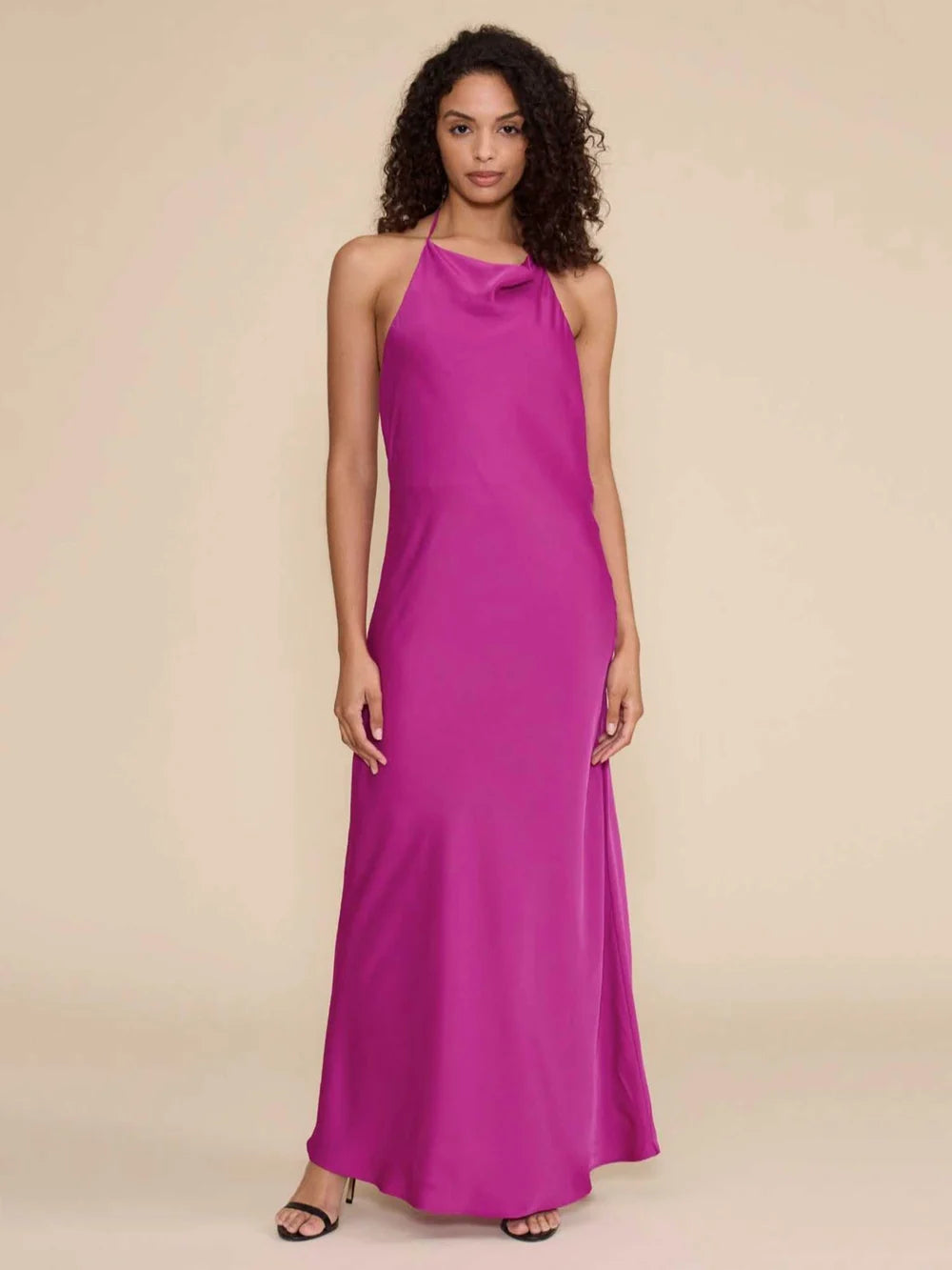 A model stands confidently in a stunning magenta halter dress with a cowl neckline, showcasing its elegant silhouette.