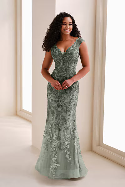 A woman stands gracefully in a stunning A-line gown made of delicate sage green fabric, featuring intricate floral embroidery.