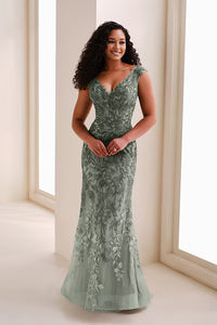 A woman stands gracefully in a stunning A-line gown made of delicate sage green fabric, featuring intricate floral embroidery.