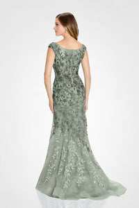 A woman is seen from the back wearing an elegant sage green A-line gown adorned with intricate floral embroidery and a flowing train.