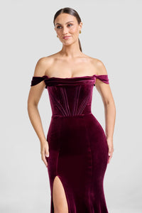 A model showcases a stunning off-the-shoulder dark chocolate gown with a sleek mermaid silhouette and a thigh-high slit.