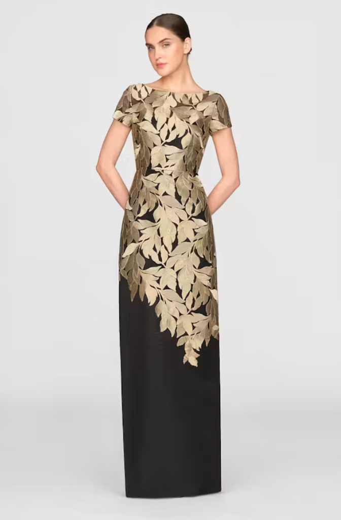 A stunning black column dress featuring intricate gold leaf appliqué detailing, perfect for elegant occasions such as gala events or black tie weddings.