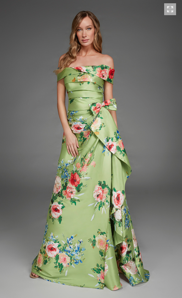 A model showcases a stunning off-the-shoulder gown in peridot green adorned with vibrant floral patterns.