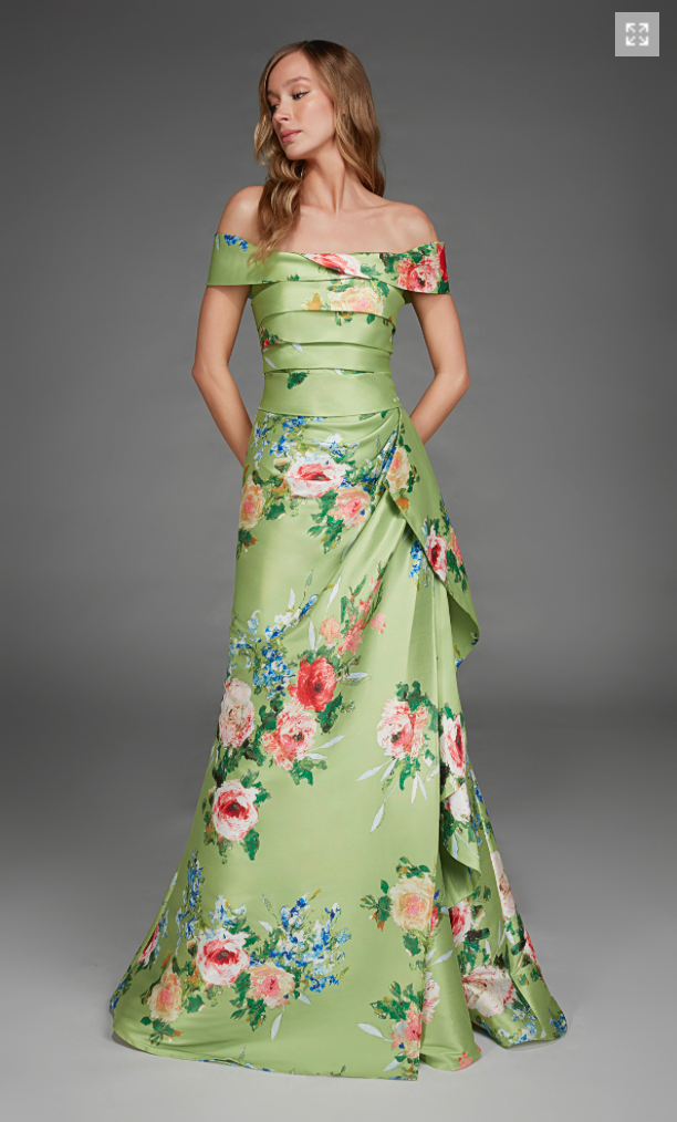 A model showcases a stunning off-the-shoulder gown in peridot green adorned with vibrant floral patterns in pink and blue.