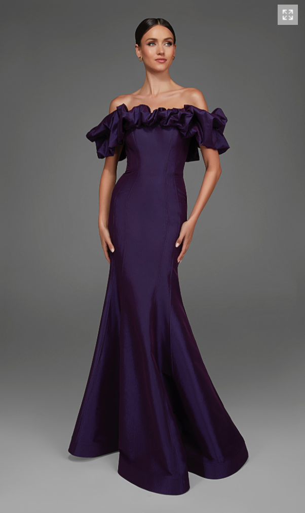 A model poses in an elegant plum gown featuring dramatic ruffled off-the-shoulder sleeves and a fitted silhouette, perfect for formal occasions like galas or black tie weddings. This stunning dress is available near Apex, Cary, and Raleigh.