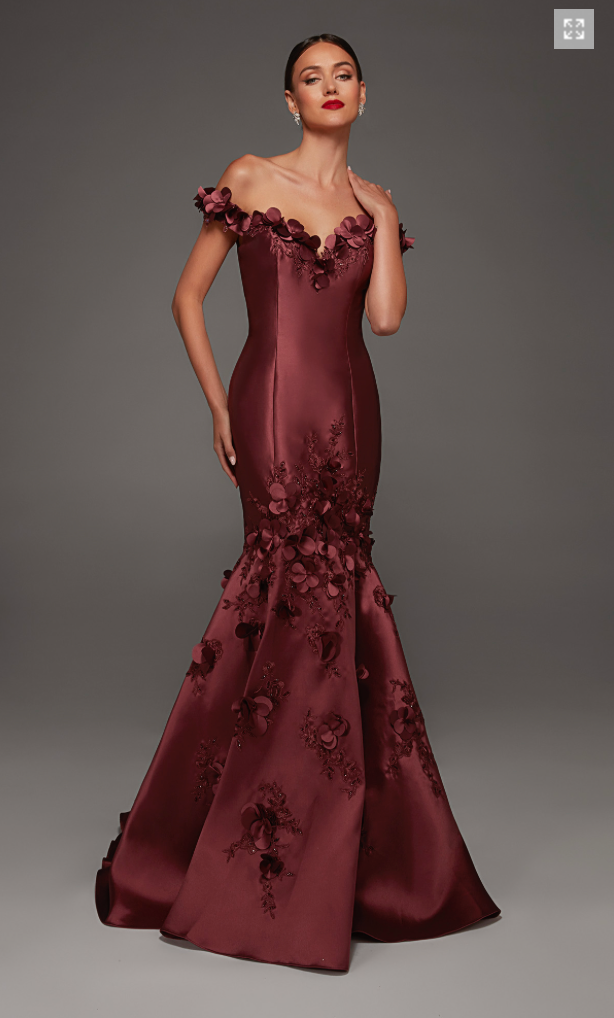 A stunning off-the-shoulder gown in a rich burgundy shade features intricate floral appliqués, hugging the body and flaring at the hem.