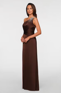 A model showcases a stylish brown one-shoulder gown featuring an elegant beaded detail on the shoulder. This versatile dress is perfect for formal occasions like weddings or galas, conveniently available near Apex, Cary, and Raleigh.