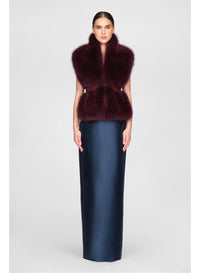 A model showcases a luxurious faux fur stole in a rich velvet fig color, paired with a sleek, floor-length navy gown.