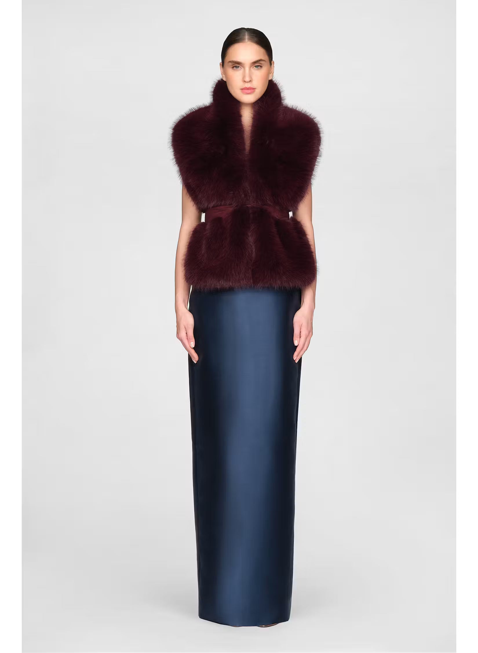 A model showcases a luxurious faux fur stole in a rich velvet fig color, paired with a sleek, floor-length navy gown.
