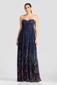 A model showcases a stunning strapless floor-length gown featuring shimmering pleated fabric with a floral design at the hem.