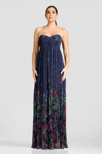 A model showcases a stunning floor-length gown featuring a strapless design with a pleated bodice and a vibrant floral pattern at the hem.