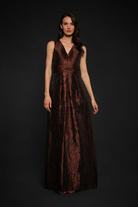 A model showcases the elegant Mariah Gown in chocolate brown, featuring a flattering V-neckline and a floor-length design.