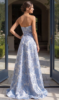 A model showcases a stunning strapless periwinkle gown with intricate floral patterns, standing gracefully in an elegant entryway.