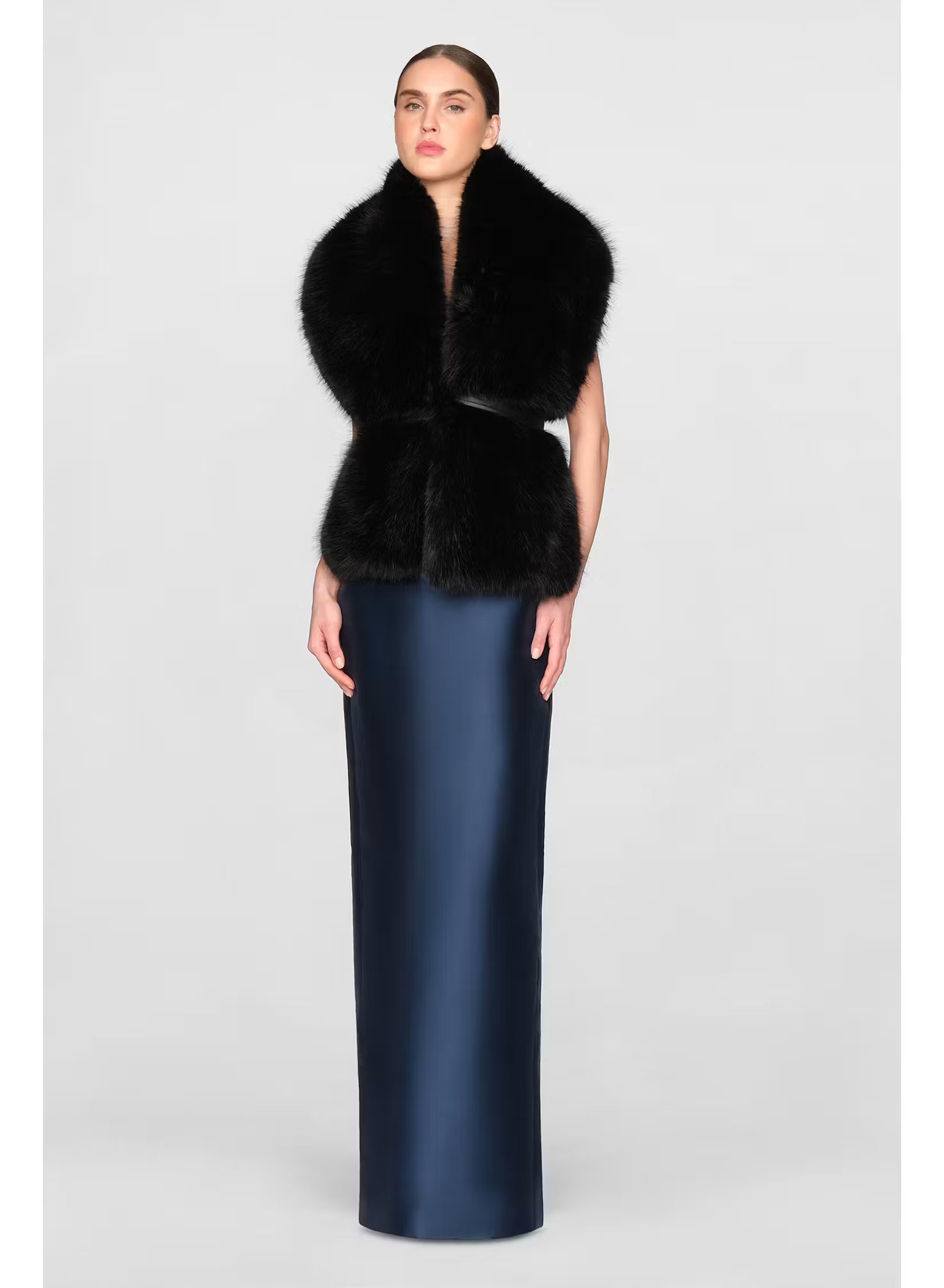 A model elegantly wears a black faux fur stole over a sleek navy gown, showcasing a sophisticated look suitable for formal occasions like black-tie weddings or galas. This stylish stole is available near Apex, Cary, and Raleigh.