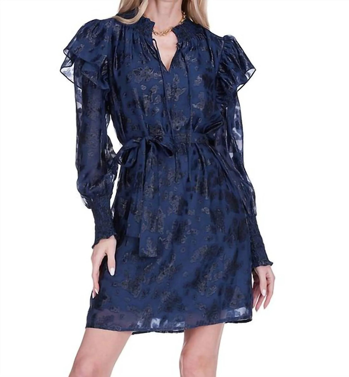A model showcases a navy shimmer mini dress with puffed sleeves and a tie waist, perfect for elegant occasions like prom or a date night. This stunning dress is conveniently located for shoppers in Apex, Cary, and Raleigh.
