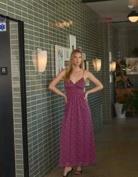 A model stands confidently in a vibrant pink floral smocked dress with thin straps, showcasing a relaxed fit.