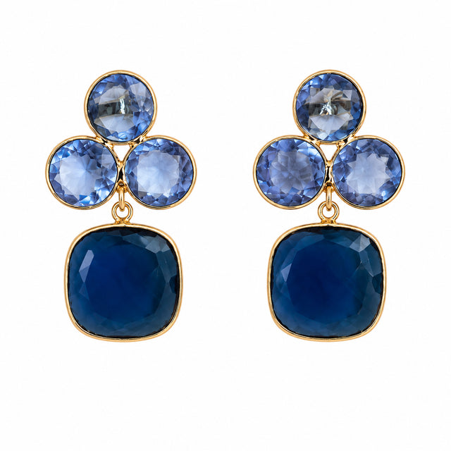 A pair of elegant earrings featuring a cluster design with three circular blue gemstones and a larger square blue stone at the bottom. These stunning earrings are perfect for formal occasions like galas or black tie weddings.