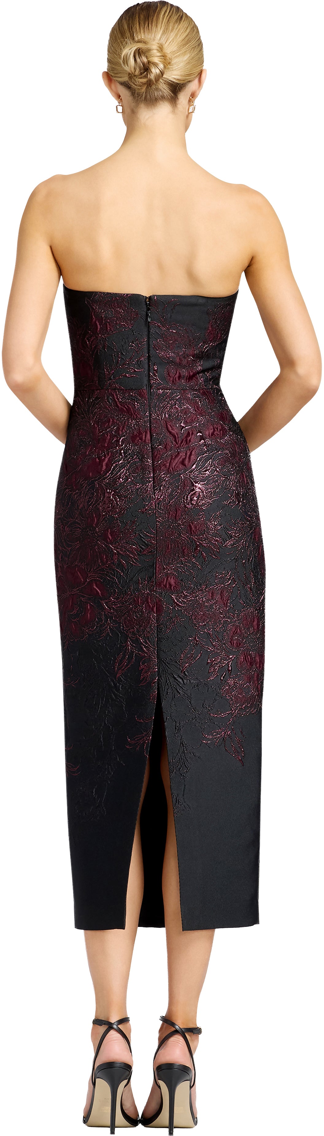 A woman is seen from the back wearing a stylish strapless black gown with intricate burgundy embroidery and a slit at the back.